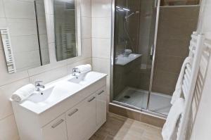 La salle de bains blanche est pourvue d'un lavabo et d'une douche. dans l'établissement La Rotonde - Appartement 1 chambre aux Chartrons, à Bordeaux
