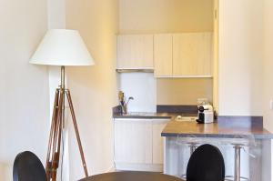 une cuisine avec une table, une lampe et des chaises dans l'établissement Saint Rémi - Appartement 1 chambre avec ascenseur, à Bordeaux