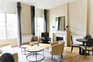 sala de estar con mesas de sillas y chimenea en Saint Rémi - Appartement 1 chambre avec ascenseur en Burdeos
