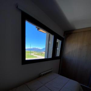 Dormitorio con ventana y cama. en Casita Sur Trevelin en Trevelín