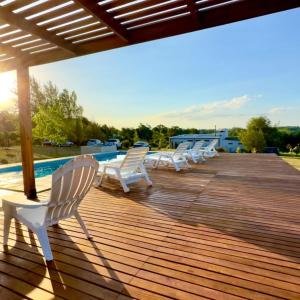 una fila de sillas blancas sentadas en una terraza de madera en Los Teritos en Tandil