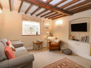 a living room with a couch and a tv at Cosy Cottage in Bawdeswell