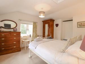 a bedroom with a bed and a dresser and a mirror at Cosy Cottage in Bawdeswell