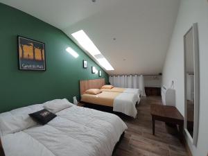 a bedroom with two beds and a green wall at La pause sous le pin in Capestang