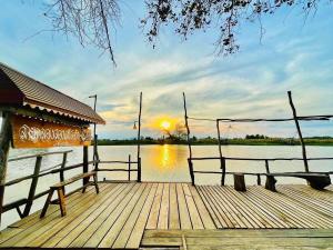 a wooden dock with two benches on a body of water at Sai Klong Song Lae Resort Pakpra Phatthalung in Phatthalung
