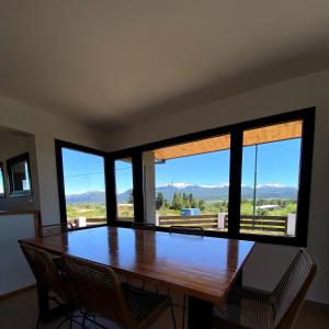 a dining room with a table and chairs and windows at Casita Trevelin in Trevelin +11 photos