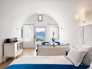 a hotel room with two beds and a window at Katikies Santorini - The Leading Hotels Of The World in Oia