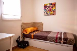 a small bedroom with a bed with an orange pillow at De El Retiro al cielo in Madrid
