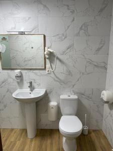 ein Badezimmer mit einem WC, einem Waschbecken und einem Spiegel in der Unterkunft Fortetsya in Chmelnyzkyj