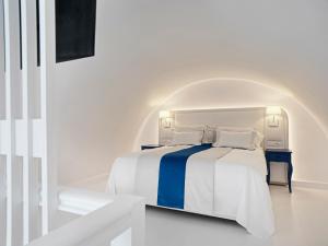 a white bedroom with a blue and white bed at Katikies Santorini - The Leading Hotels Of The World in Oia