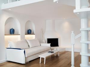 a white living room with a couch and a table at Katikies Santorini - The Leading Hotels Of The World in Oia