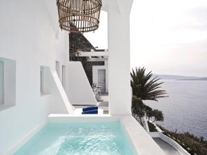 a swimming pool on the side of a house with the ocean at Katikies Santorini - The Leading Hotels Of The World in Oia