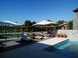 a swimming pool with two umbrellas and chairs next to a swimming pool at Lom Suites in Merlo