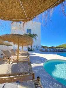 ośrodek z basenem, krzesłami i słomianym parasolem w obiekcie The Olive Boutique Suites & Spa w mieście Cala Llonga