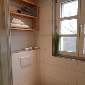 baño con paredes de azulejos blancos y ventana en Ferienwohnung Niederrhein, en Wesel