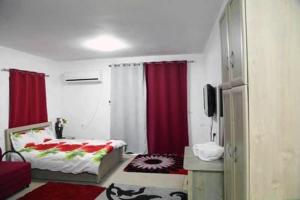 - une chambre avec un lit, des rideaux rouges et une télévision dans l'établissement Aseel hostel, à Majdal Shams