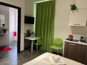 1 dormitorio con cortina verde y mesa con sillas en Bnbook Residence Matteotti, en Novara