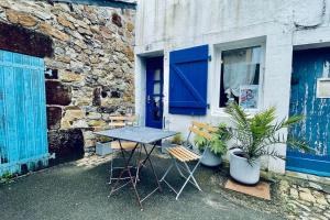 a table and chairs next to a building with a blue door at La p'tite sardine in Camaret-sur-Mer
