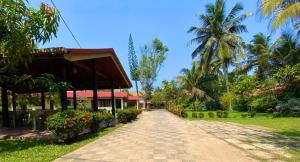 a path in front of a building with palm trees at Hotel TK Green Garden in Matara