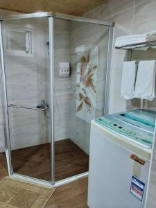 a shower with a glass door in a bathroom at Happiness B&B in Linbian