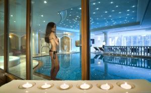 une femme en bikini debout à côté d'une piscine dans l'établissement Wellness Hotel Gran Risa***S, à La Villa