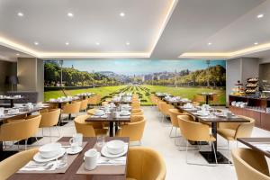 a dining room with tables and chairs and a painting of a stadium at Empire Marquês Hotel in Lisbon