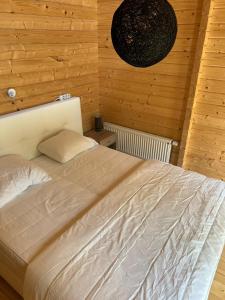 ein Schlafzimmer mit einem großen Bett an einer Holzwand in der Unterkunft Villa Bartje in Schoonebeek