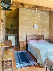 - une chambre avec un lit et un mur en briques dans l'établissement Chalé buraco do tatu, à Conceição da Ibitipoca