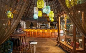 a restaurant with a bar with yellow chairs and lights at Resort Vidanta Riviera Maya in Puerto Morelos