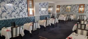 un restaurante con mesas y sillas blancas y papel pintado azul y blanco en Ocean View Hotel en Shanklin