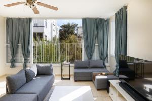 a living room with a couch and chairs and a large window at Gordon Seaside 4BDR apt in TLV in Tel Aviv