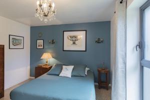 um quarto azul com uma cama e um lustre em La Conserverie em Blois