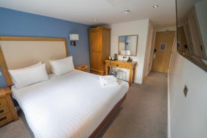 um quarto com uma grande cama branca e um espelho em The Waterside Hotel and Leisure Club em Manchester