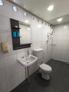 La salle de bains blanche est pourvue de toilettes et d'un lavabo. dans l'établissement Tiongman Scubadive & Lodge, à l'Île Tioman