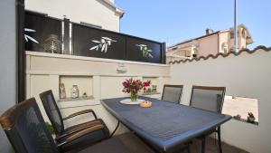 una mesa negra con sillas y un jarrón de flores en el balcón en Apartment Igor en Novigrad Istria