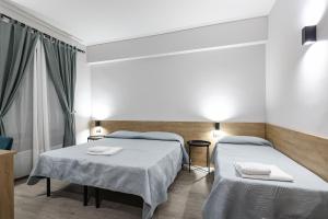a hotel room with two beds and a window at Seven Kings Relais in Rome