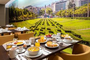 a table with plates of food on it in a restaurant at Empire Marquês Hotel in Lisbon