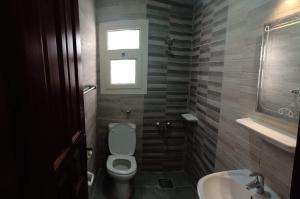 a bathroom with a toilet and a sink and a window at L’amour Hotel apartment in Marsa Matruh