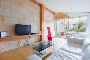 a living room with a couch and a tv at Maison spacieuse avec Jardin et Garage in Bordeaux