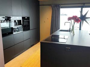a kitchen with black cabinets and a counter with a vase of flowers at Holiday home Drangedal in Drangedal