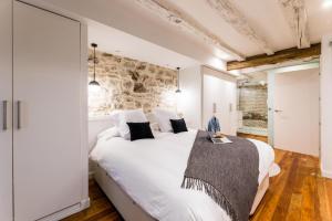 1 dormitorio con cama blanca y pared de piedra en AMELIA suite apartment en San Sebastián