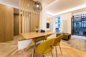 uma sala de jantar com uma mesa de madeira e cadeiras amarelas em CHURRUCA suite apartment em San Sebastián