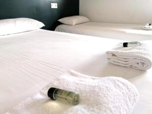 ルマンにあるエクロ ホテルズ ル マンの白いベッドに敷かれたワイン1本