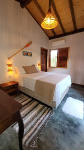 a bedroom with a large bed and a table at Bons Ventos Camping e Glamping in Barra Grande