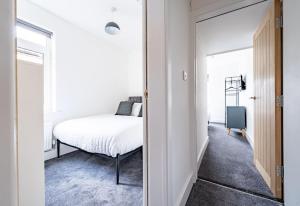 a white bedroom with a bed and a mirror at Isaacs View - First Floor Apartment in Cleethorpes