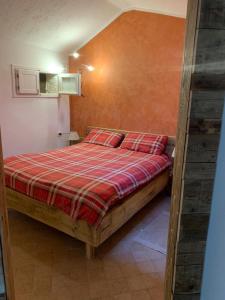 a bedroom with a bed with a red plaid blanket at La tana club Suite Oro & Argento in Serina