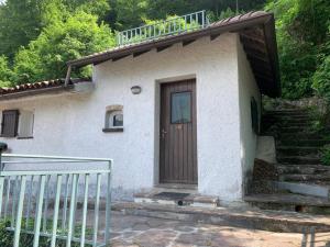 a small house with a wooden door and stairs at Paradise La Tana in Serina