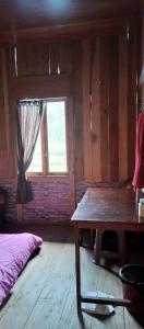 TomohonにあるTalaga Tomohon Home Stay and Fishing Pondの木製テーブルと窓が備わる客室です。