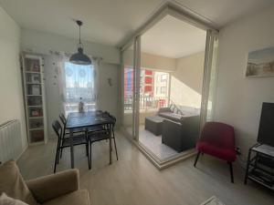 a living room with a table and a red chair at APPARTEMENT LUMINEUX SUR LE PORT! 5 MN DE LA PLAGE AVEC PARKING PRIVE in Cap d'Agde