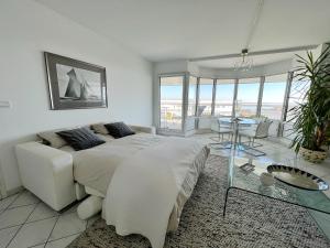 - une chambre blanche avec un grand lit et une table dans l'établissement L'Océane - Magnifique vue mer, à La Rochelle